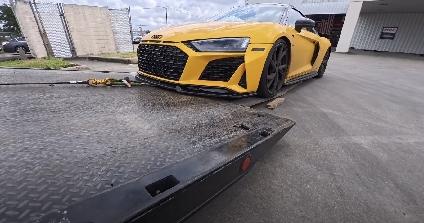 Yellow Audi sports car secured on a flatbed tow truck after a battery failure in Islip, NY